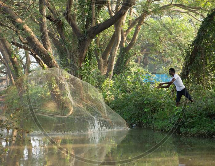 A Fisherman Throwing Fishing Net In an Water Channel