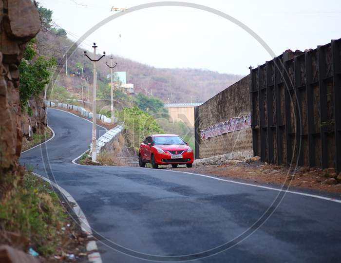 A Red Baleno Car parked alongside the road
