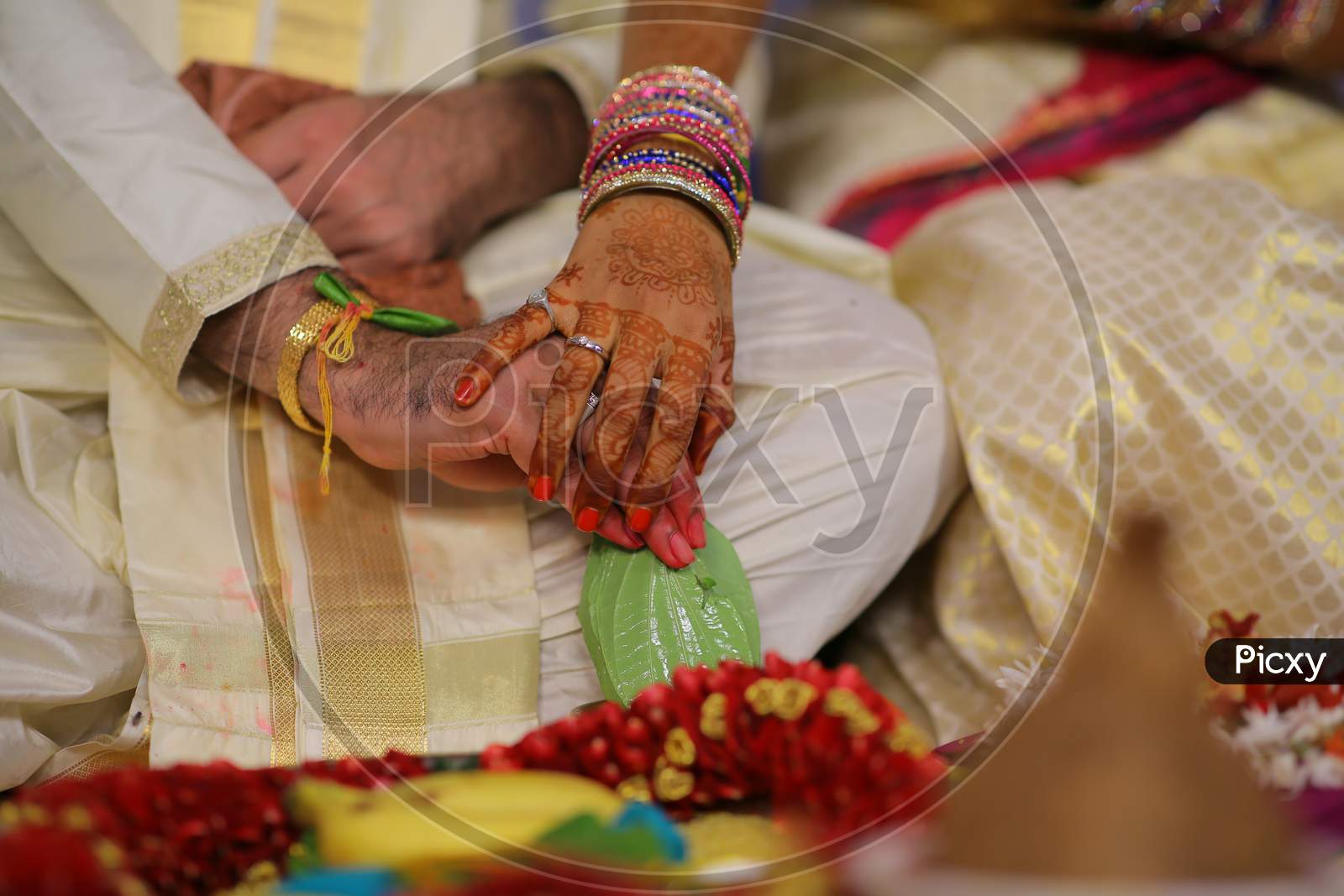 Indian Bride and Groom holding hands during puja