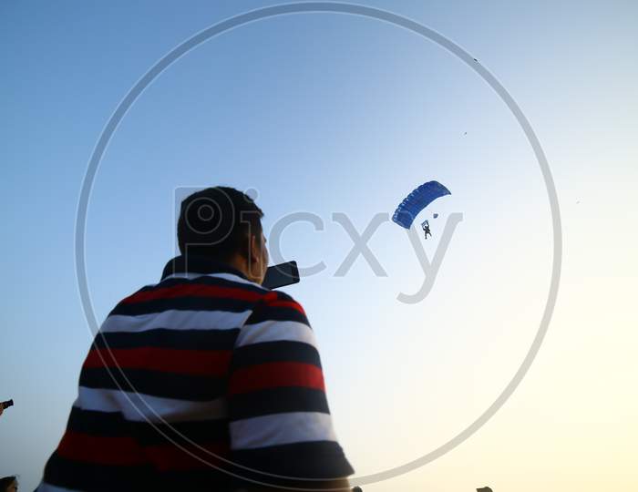 Indian Man taking a picture of paragliding with phone