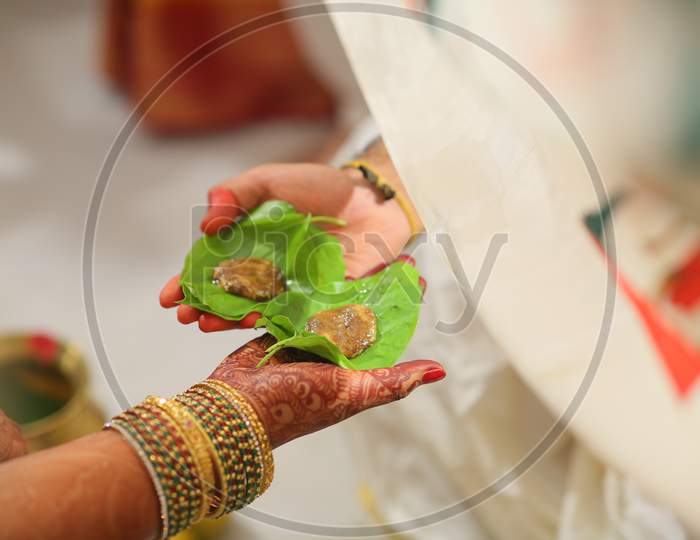 Indian bride and bride groom holding cumin and jaggery