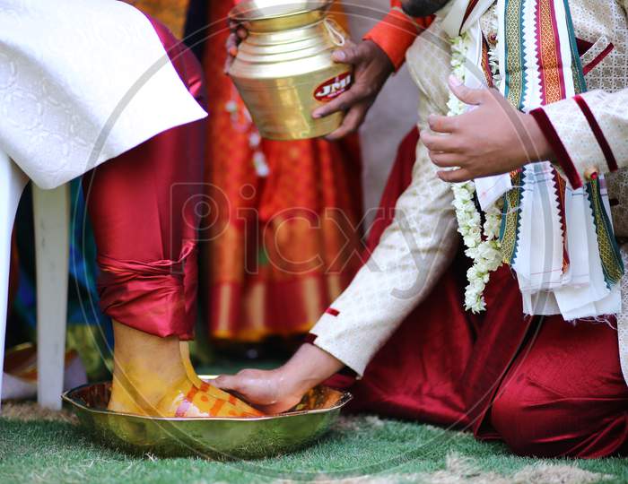 Indian man washing bride groom's legs during wedding
