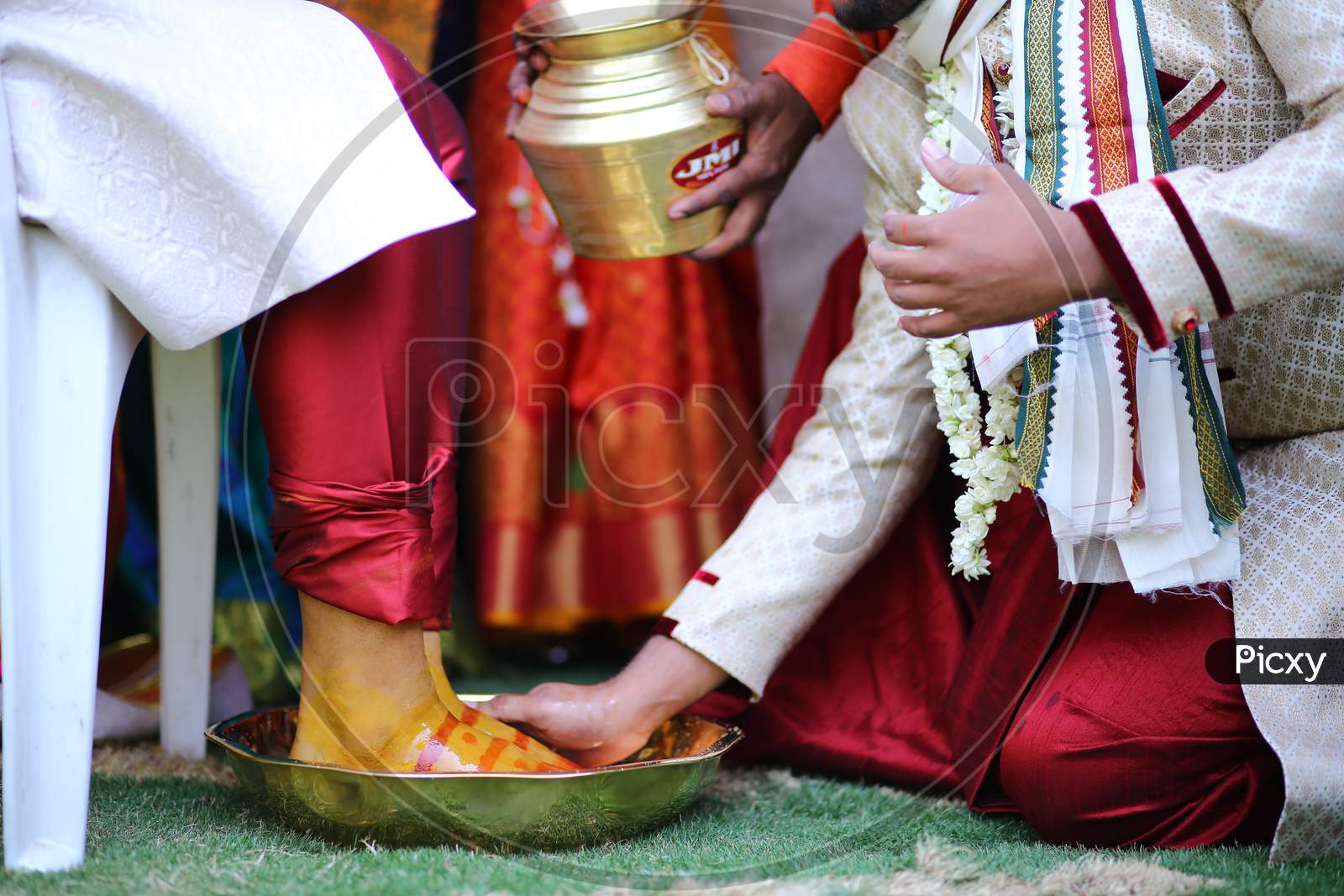 Indian man washing bride groom's legs during wedding