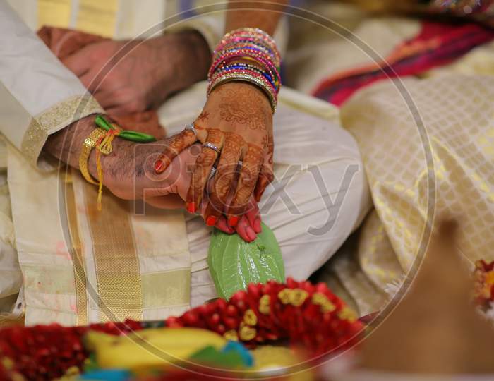 Indian Bride and Groom holding hands during puja