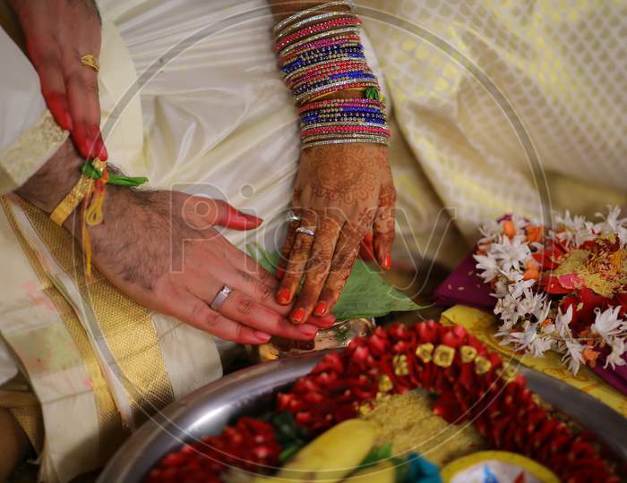 Indian bride and groom touching hands during puja