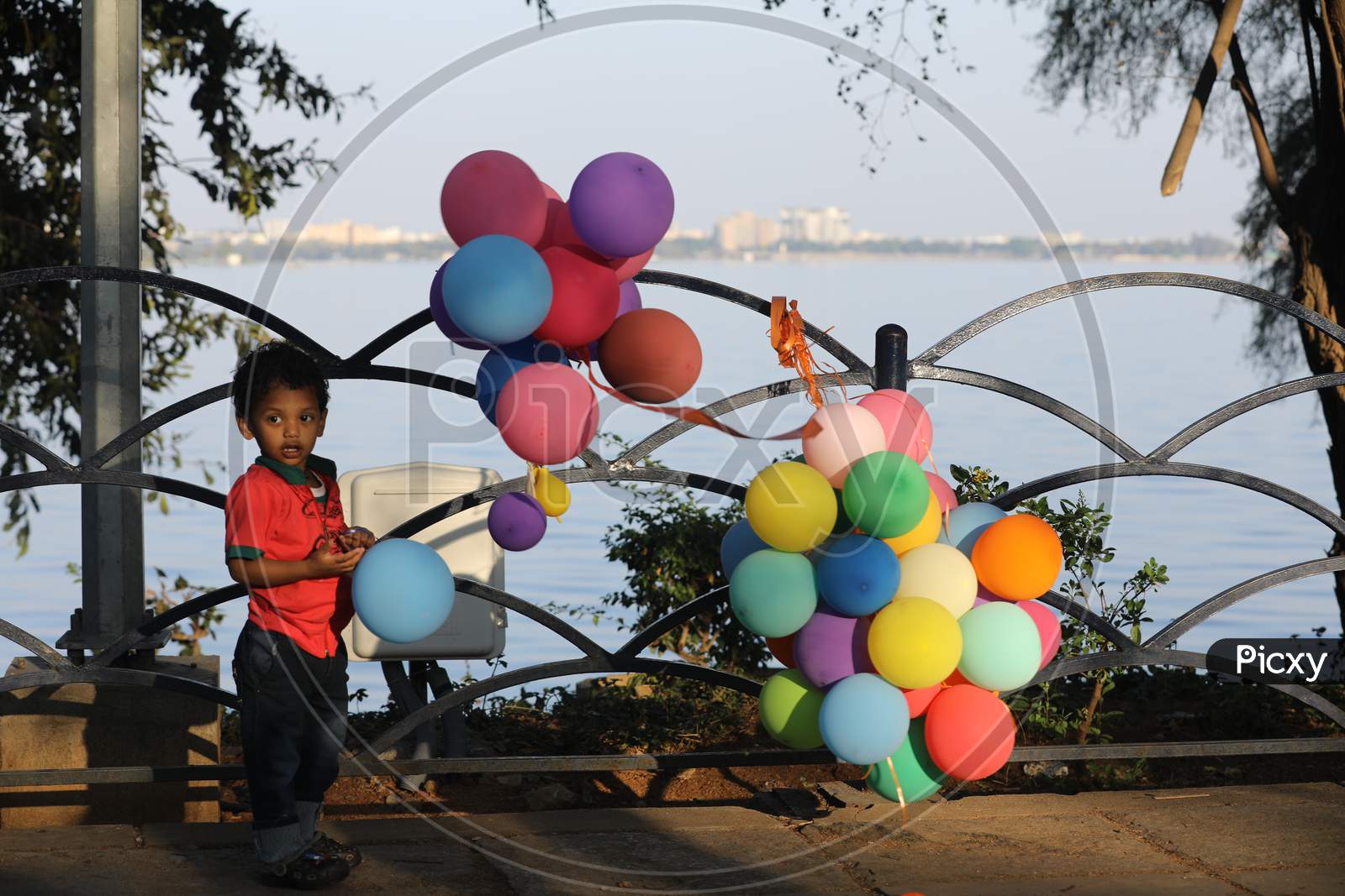 Indian Boy Playing With Colourful Balloons At a Lake Front