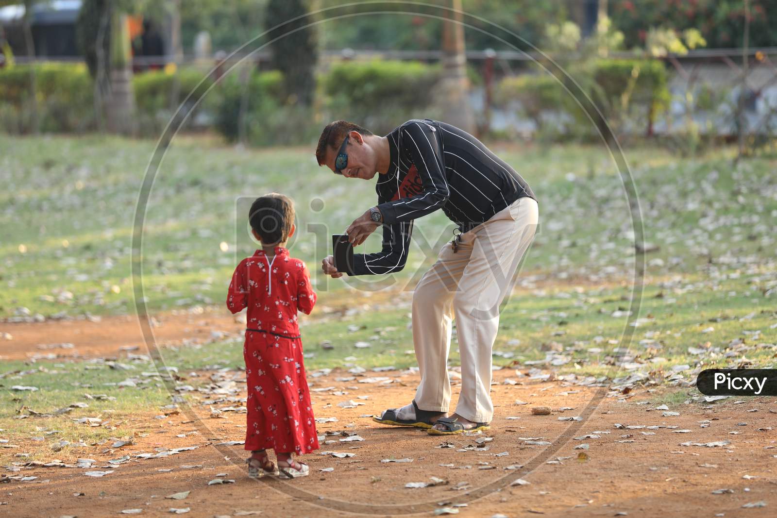 A Father Taking Picture Of A Girl Child in an Park