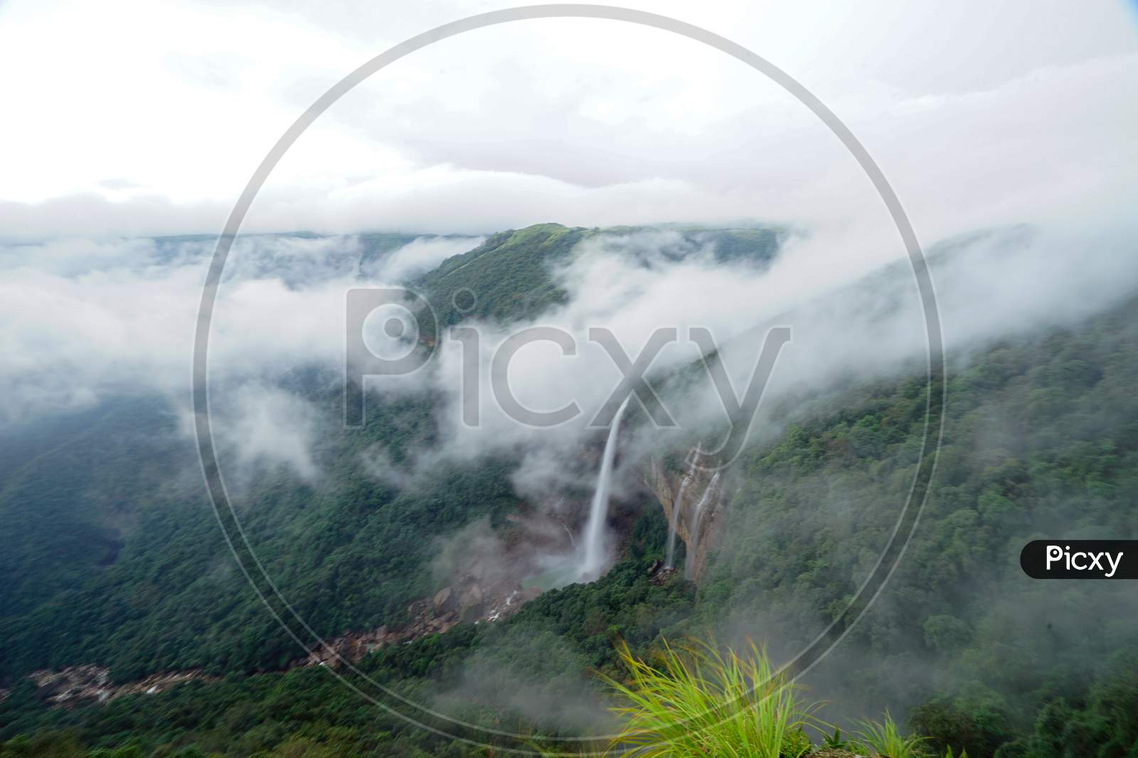 View of waterfalls with clouds covered mountains