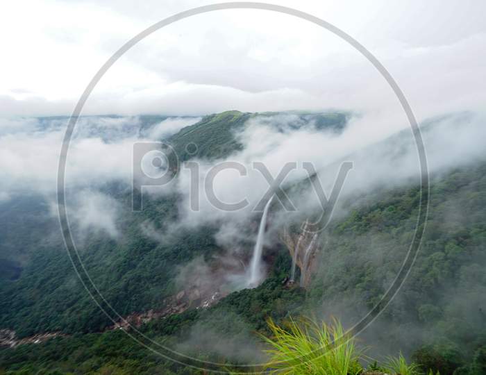 View of waterfalls with clouds covered mountains