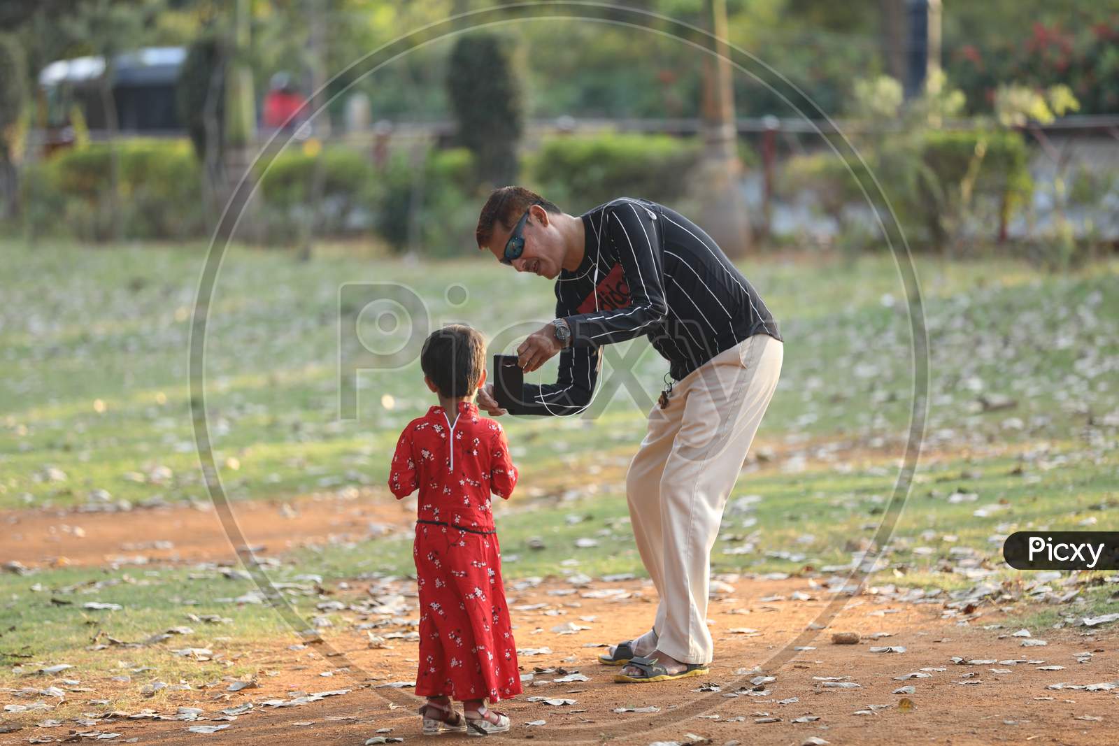 A Father Taking Picture Of A Girl Child in an Park