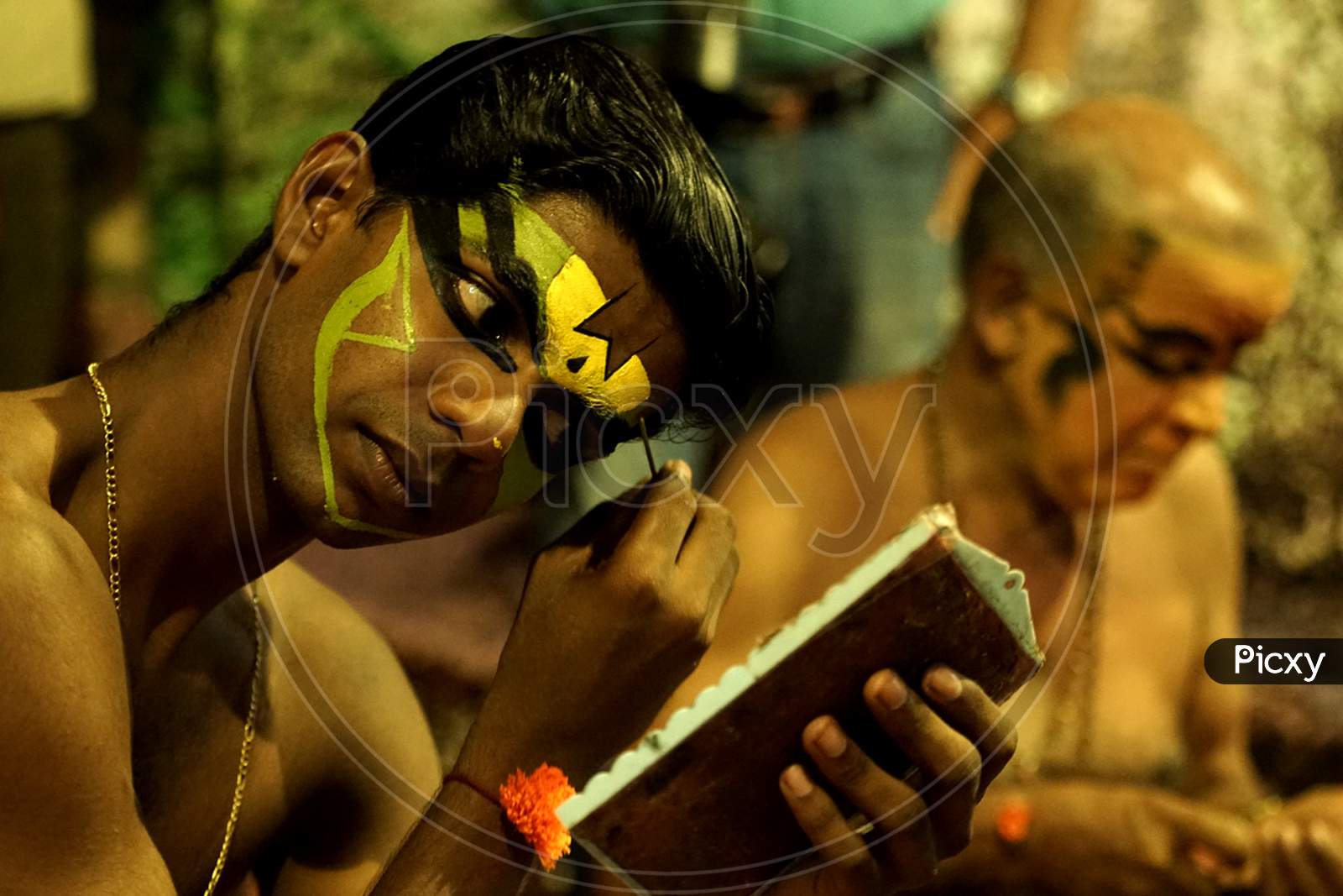 Indian man putting yellow face paint