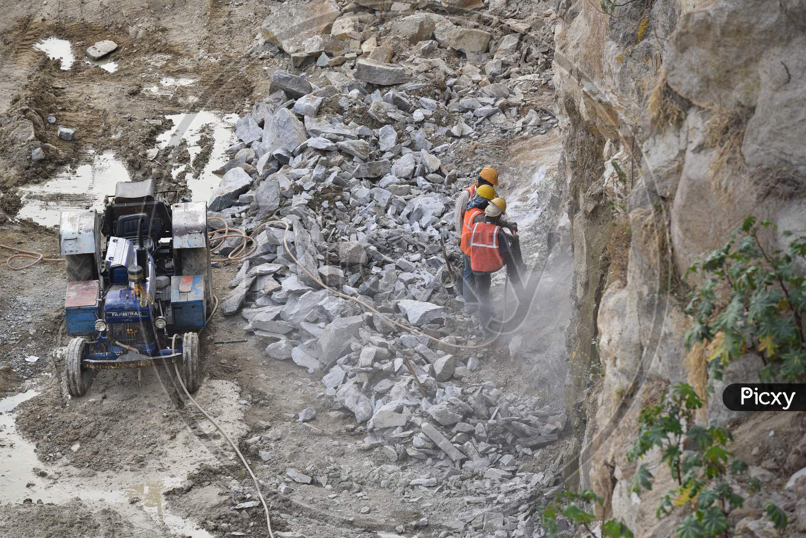 Construction workers drill a huge rock with a vacuum driller machine