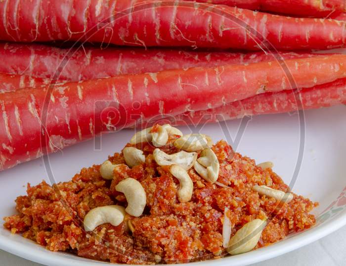 Carrot Halwa   Served in Plate With Fresh Carrots  Over White Background