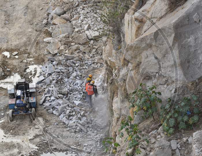 construction workers drilling a huge stone