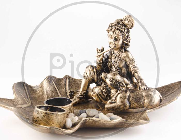 Brass Idol Of Lord Krishna Over An Isolated White Background