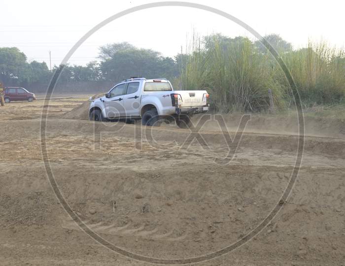 Side view of Isuzu Car moving along the dirt road