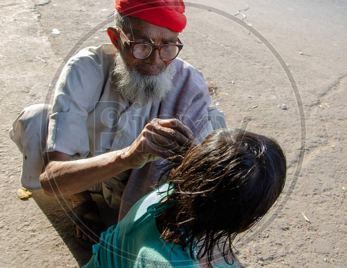 An Elderly Man Performing  Ear Piercing  To an Small Child