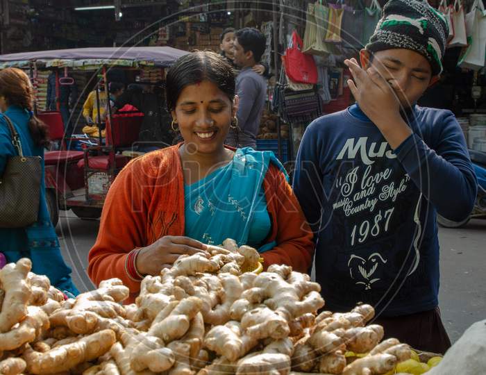 An Indian Woman Buying Ginger From A Vendor Stall At a   Market