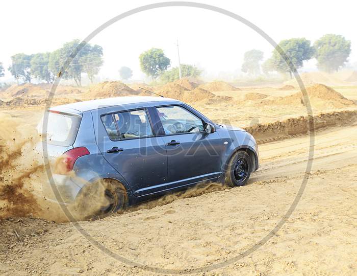 Suzuki Swift car moving on the mud road