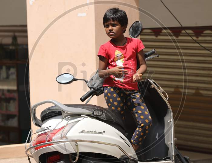 Indian Girl Child Standing on a Scooty