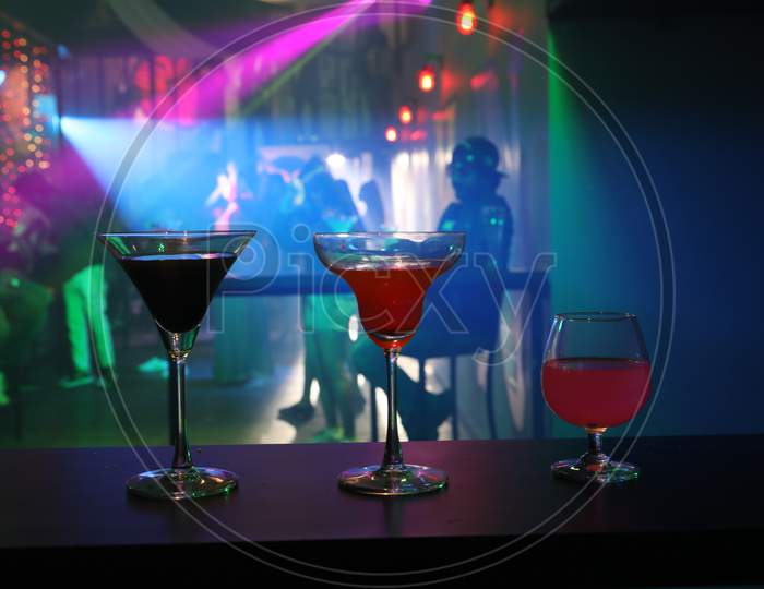 Cocktail Glasses on a Bar Table Counter With Neon Lights Background
