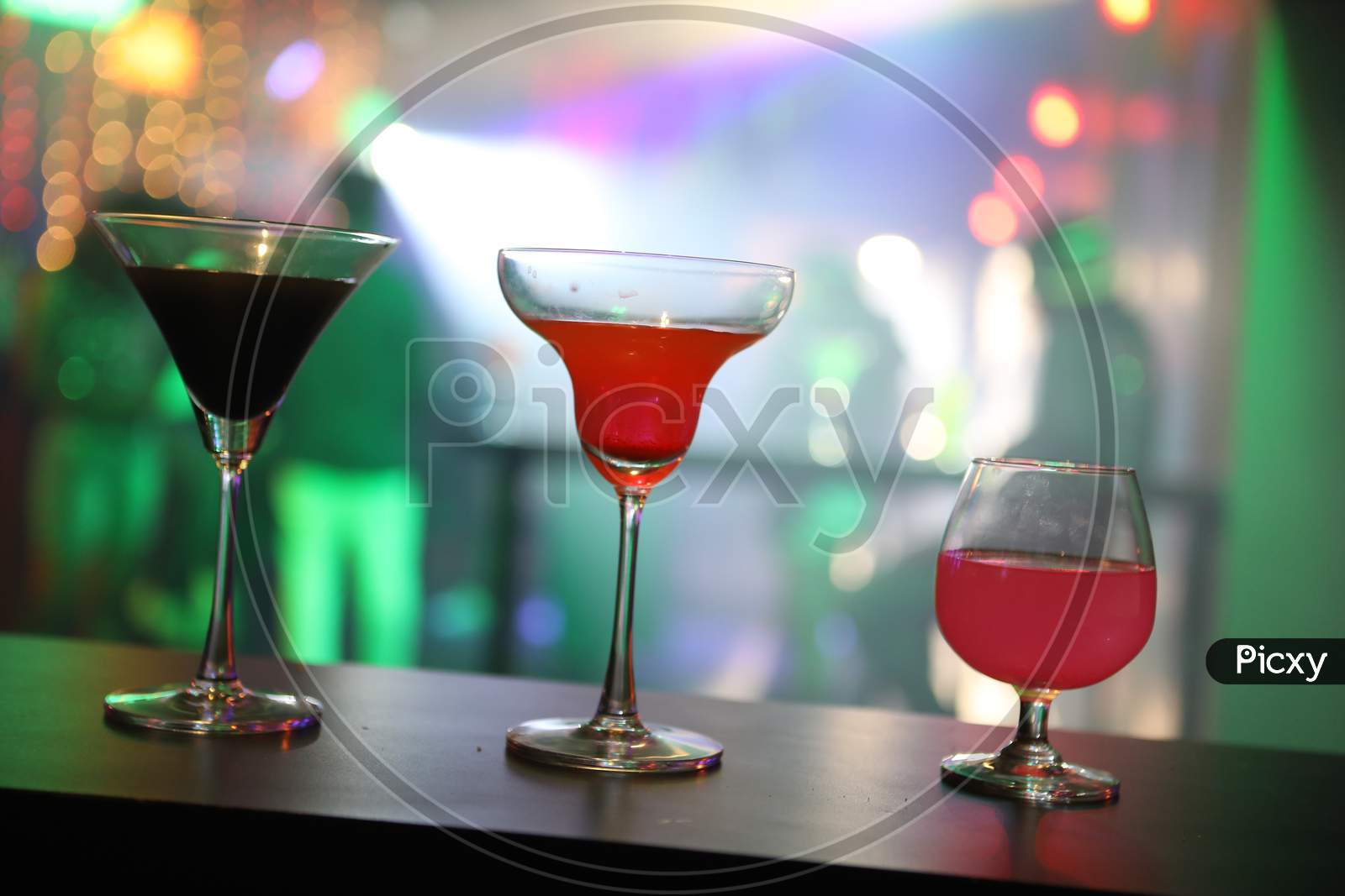 Cocktail Glasses on a Bar Table Counter With Neon Lights Background