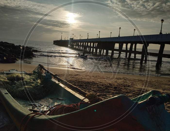 A Fishing Boat At an Fishing Hamlet With A Pier in Background  At Pondicherry Beach