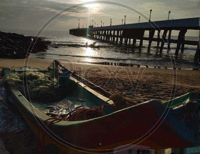 A Fishing Boat At an Fishing Hamlet With A Pier in Background  At Pondicherry Beach