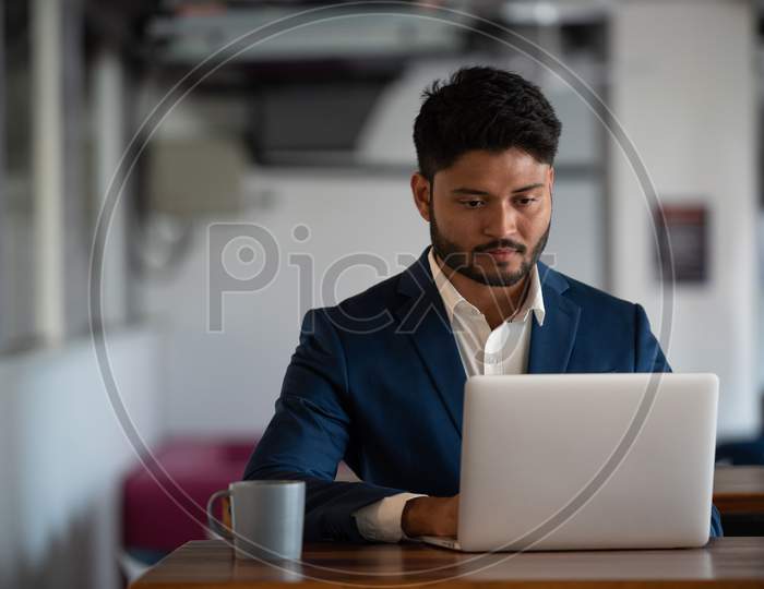 Indian  Businessman Using  Laptop at an Office  Desk
