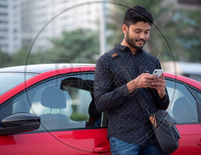 Indian Student Using Mobile By Standing Near a Car