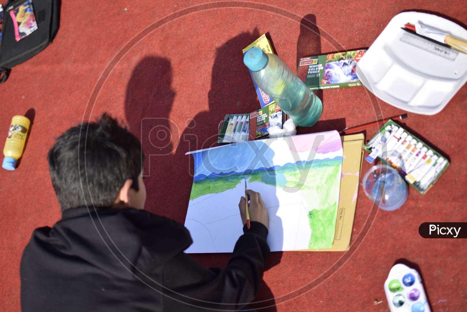 Indian School boy painting with a brush during outdoor art class