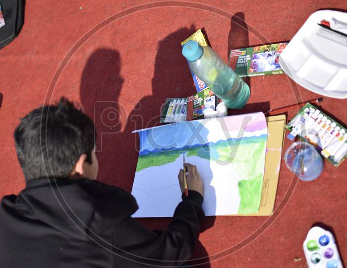 Indian School boy painting with a brush during outdoor art class