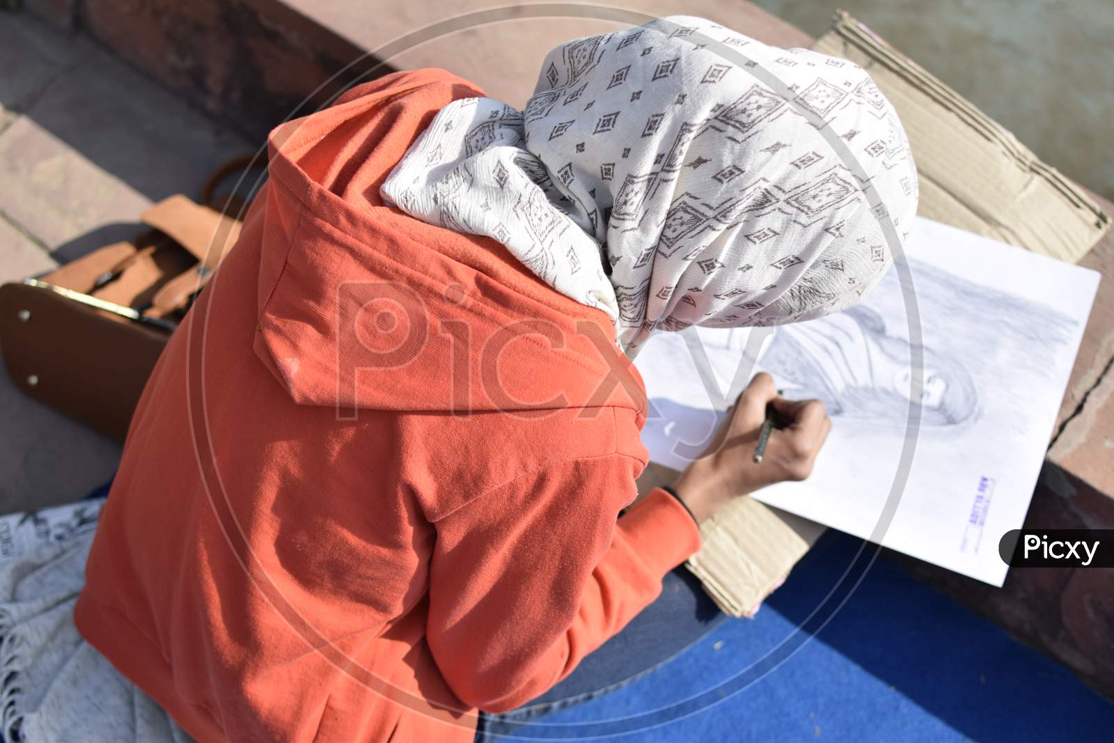 Indian girl student coloring the sketch outdoors