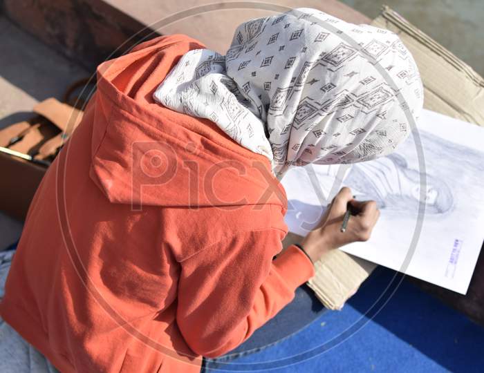 Indian girl student coloring the sketch outdoors