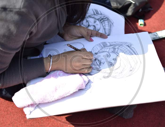 Indian School girl drawing a portrait sketch during a competition