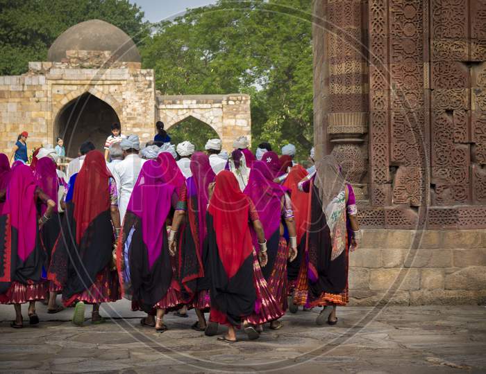 Women wearing traditional Rajasthani dress walks inside the Qutab Minar complex.
