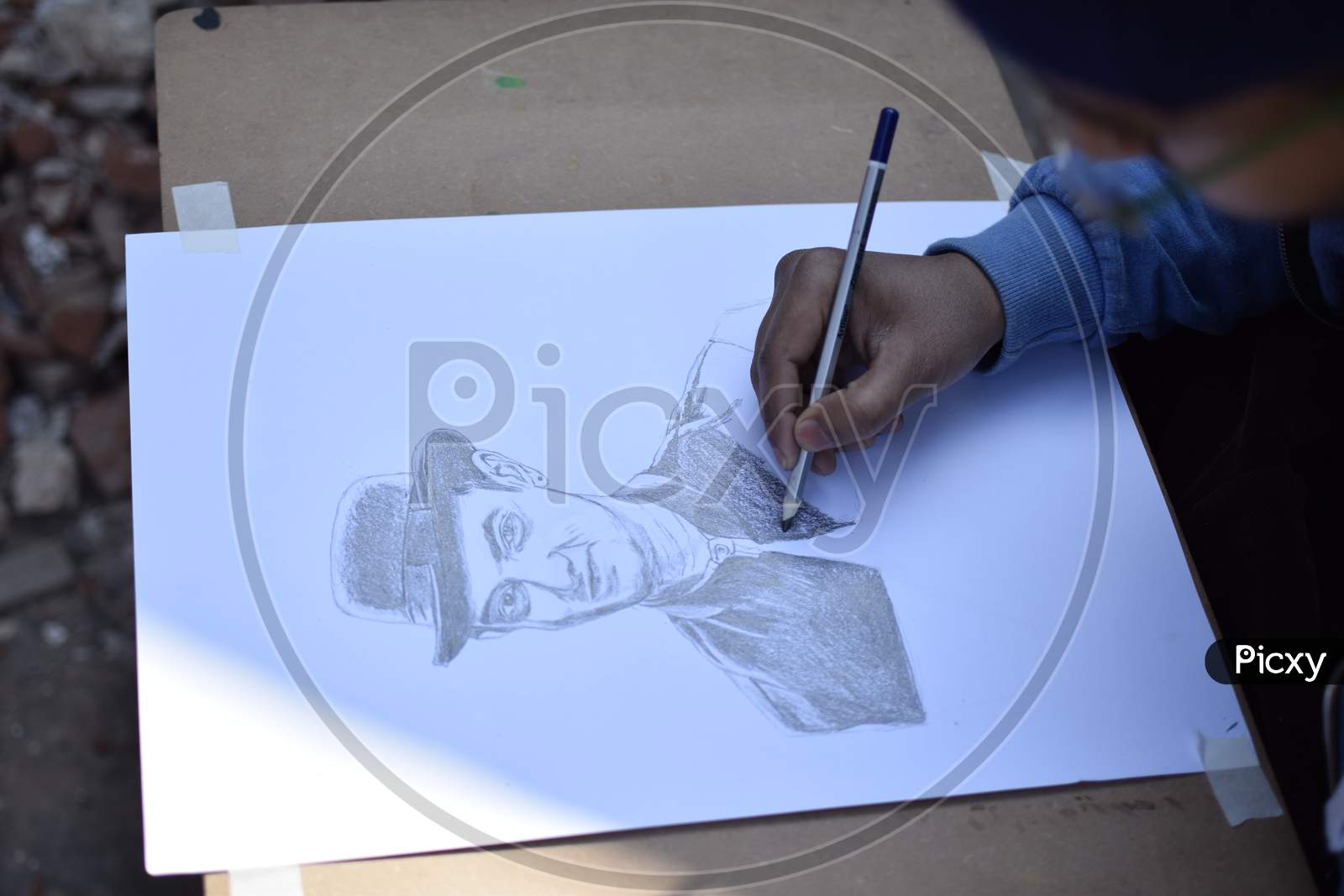 A School student drawing a man's portrait wearing a hat