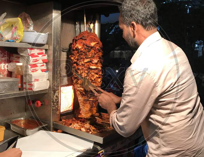 Shawarma seller cutting the chicken