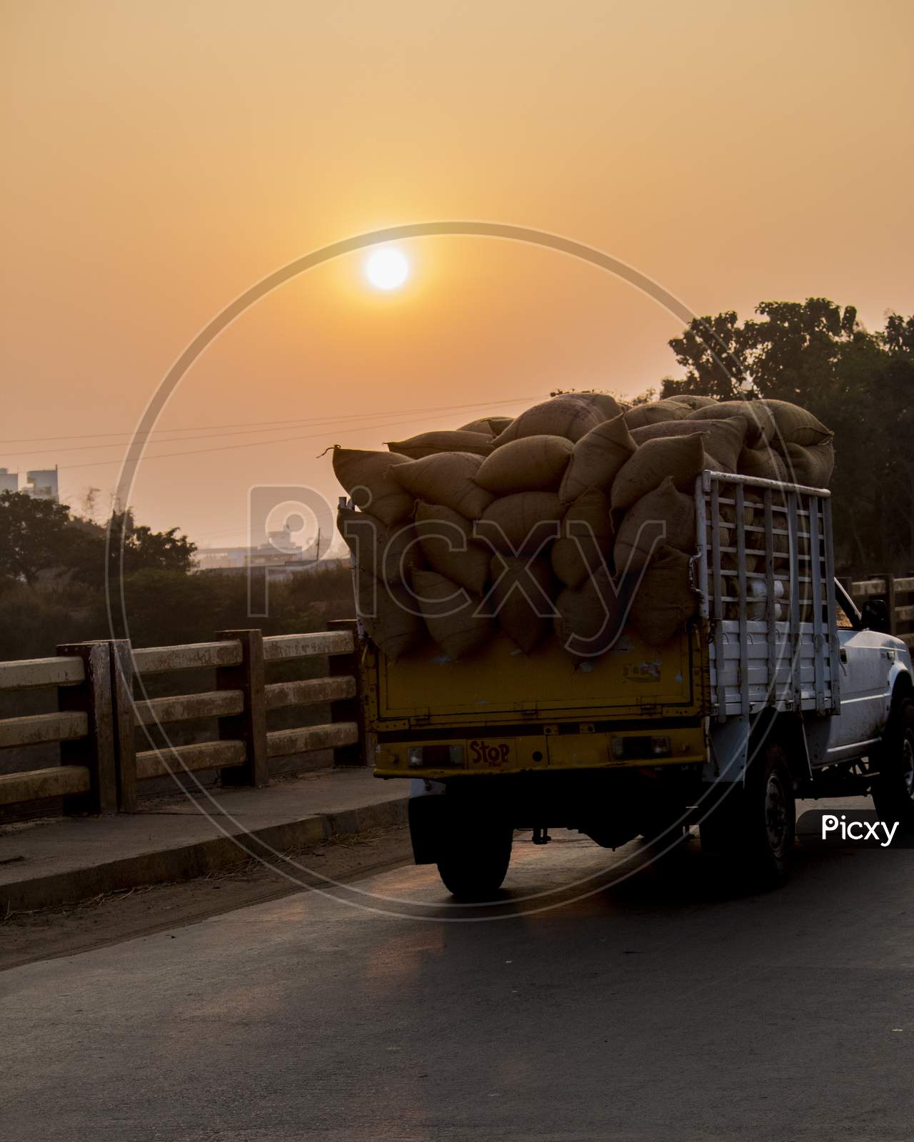 A Mini Truck  On a Bridge With Sunset Sun In Background