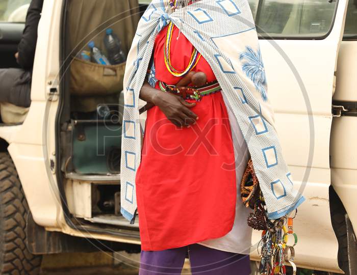 African Tribal woman standing by a car
