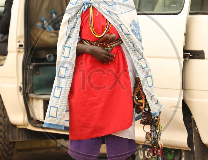 African Tribal woman standing by a car with handicraft bracelets