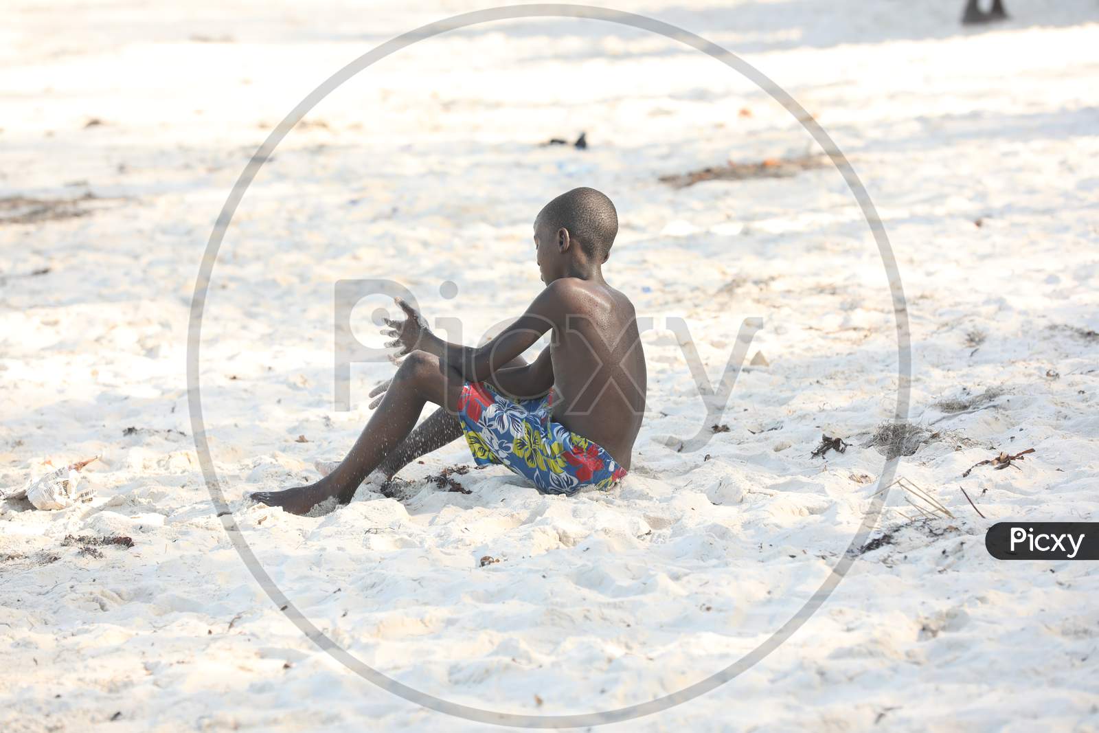 A Shirtless Kenya boy sitting by the beach