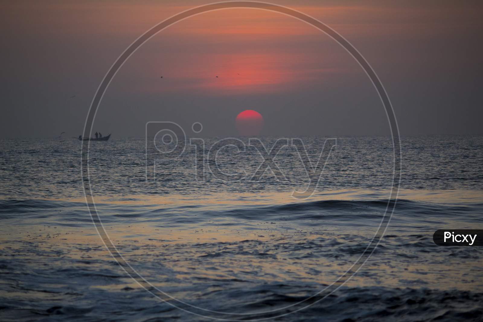 Silhouette Of Fishing Boat On Sea With Sunset Sun In Background