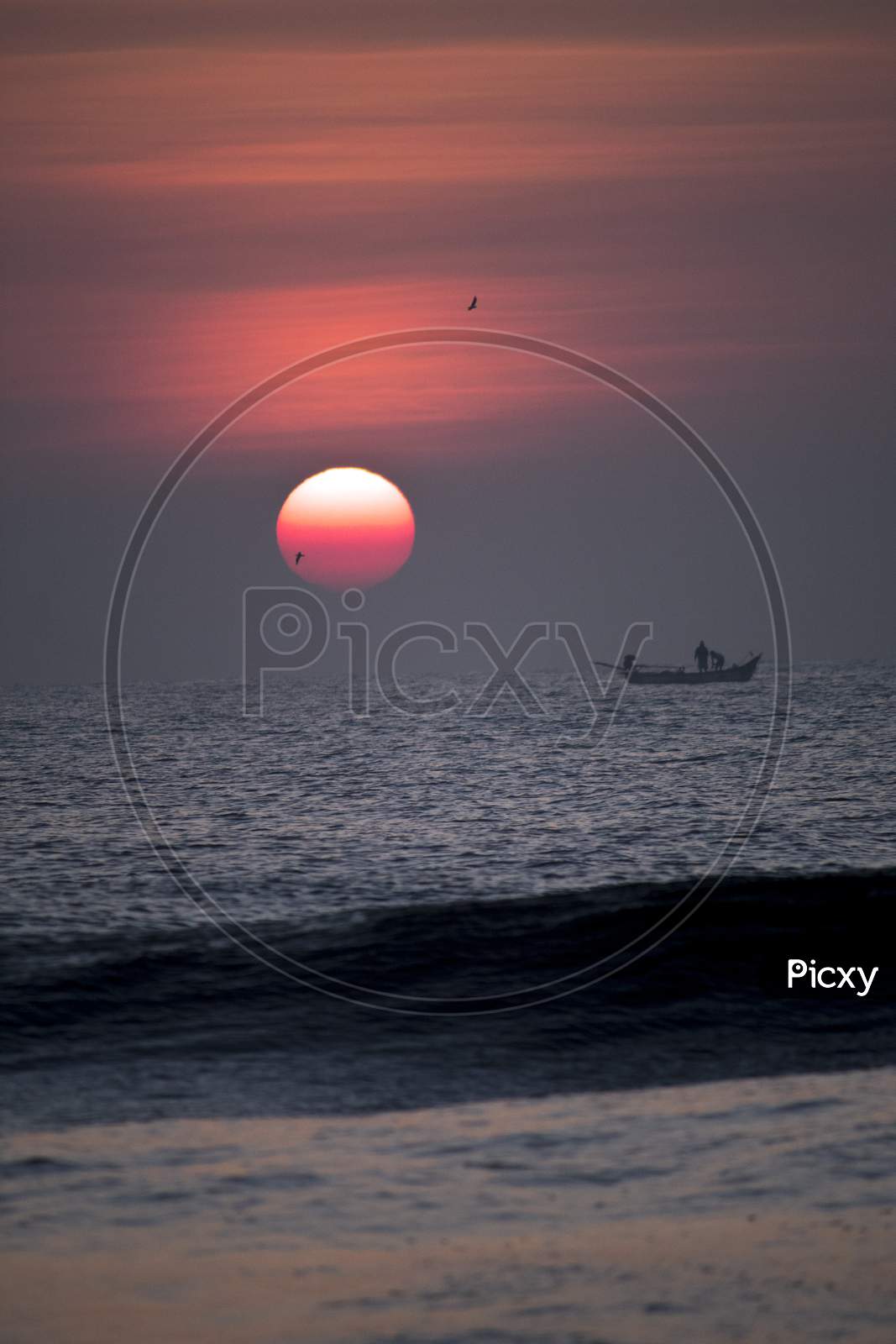 Silhouette Of Fishing Boat On Sea With Sunset Sky  In Background