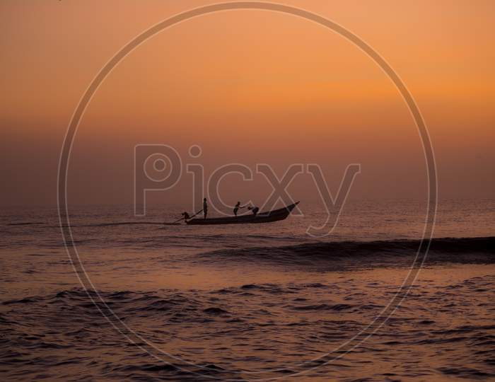 Silhouette Of Fishing Boat On Sea With Sunset Sun In Background