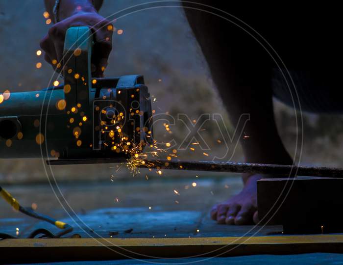 A Cutter Cutting Iron Strings With Fire Sparkles In an Workshop