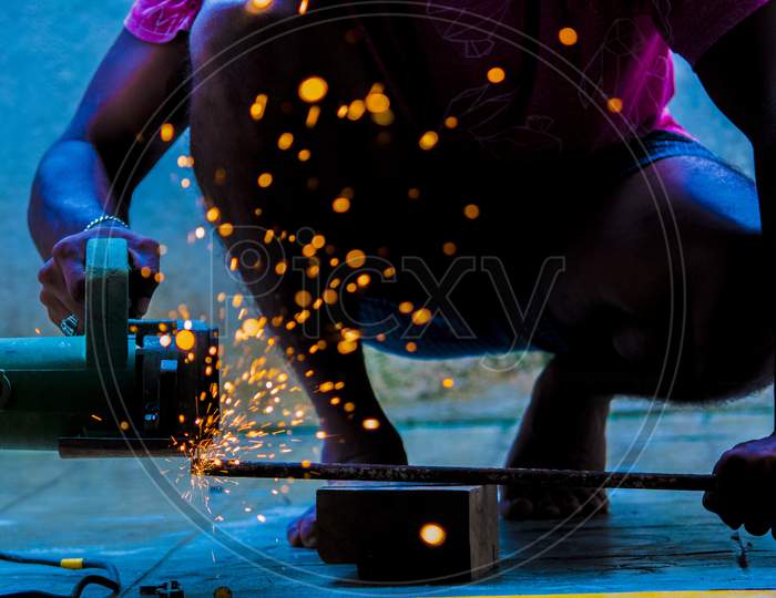 A Cutter Cutting Iron Rods  With Fire Sparkles In an Workshop