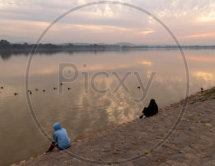 people sitting on the stairs near sukhna lake chandigarh in the morning