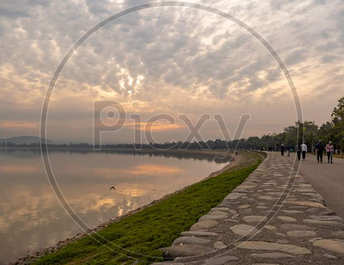 people walking alongside sukhna lake in the morning at chandigarh