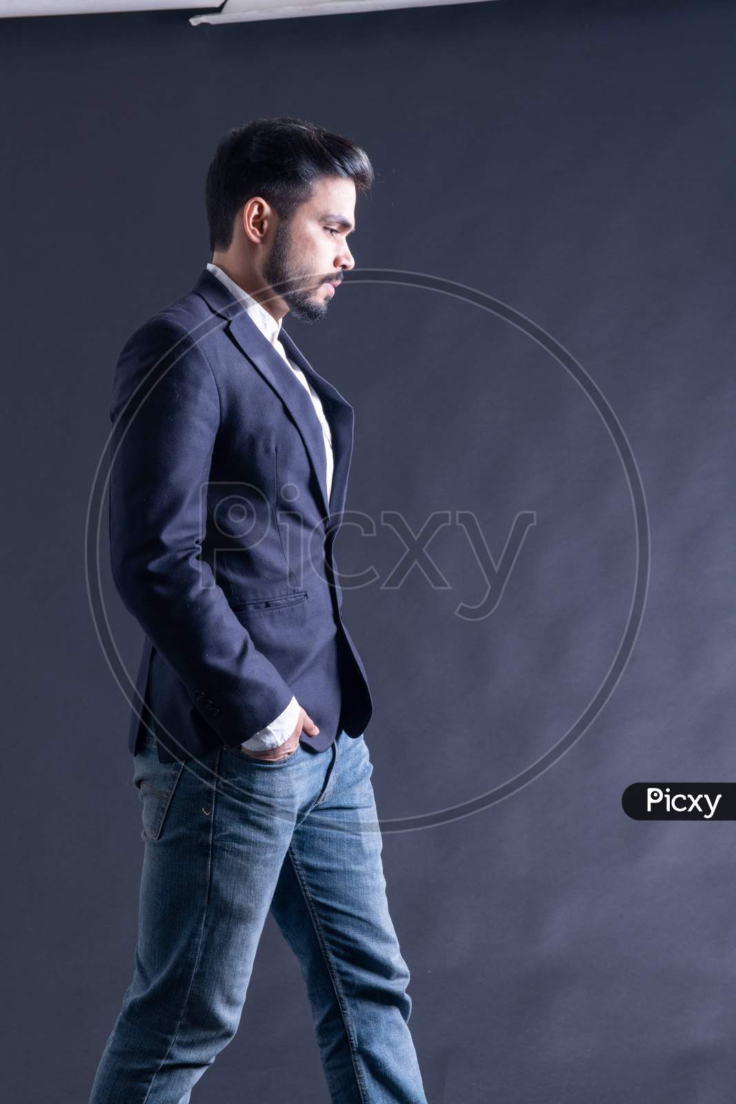Indian Young Male Model Posing Wearing A Suite Over An Black grunge wall Background